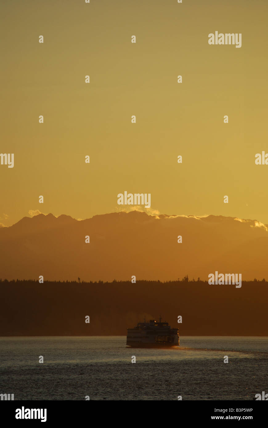 A Washington State ferry leaves Edmonds, WA for Kingston, WA. The Olympic Mtns. are seen in the background. Stock Photo