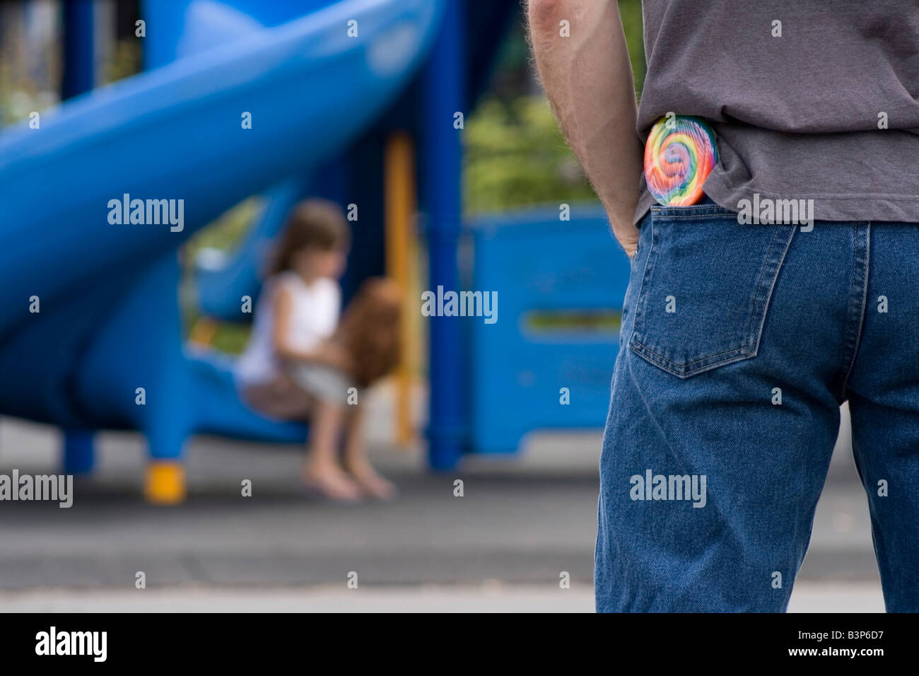 Man with a lollipop watching a young girl on the playground Stock Photo