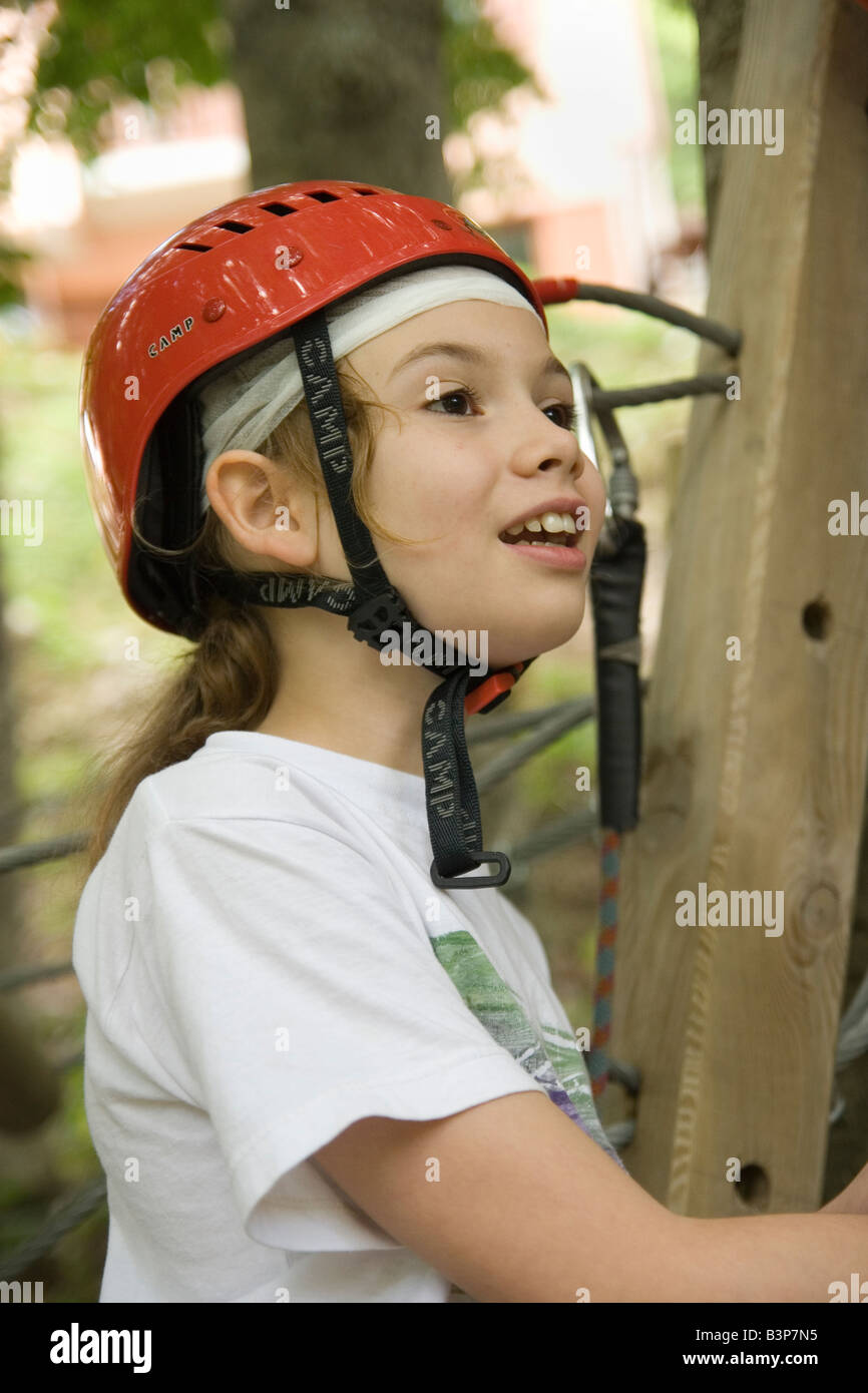 child wearing safety helmet hooks cable to rope in wooded adventure