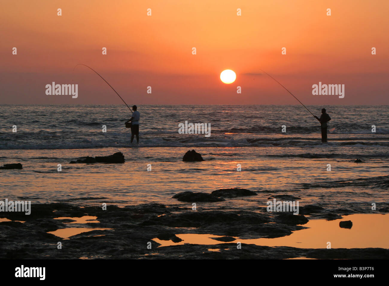 Israel Achziv people fishing at sunset Stock Photo