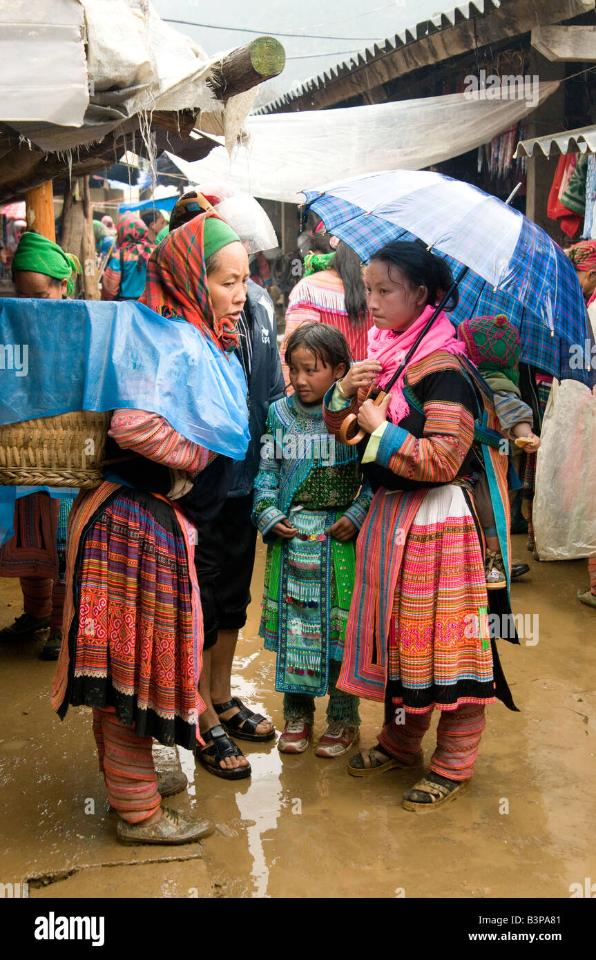 A Flower Hmong mother and children standing in the rain Muong Khuong market Northern Vietnam Stock Photo