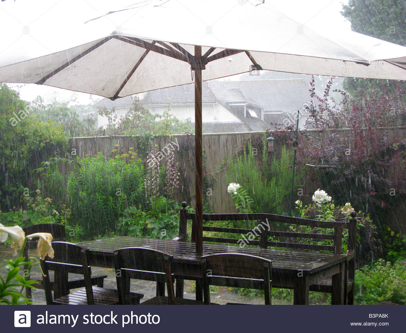 Rainy Summer Weather In A Garden With Table Chairs And Sunshade Rainy Summer Weather In A Garden With Table Chairs And Sunshade