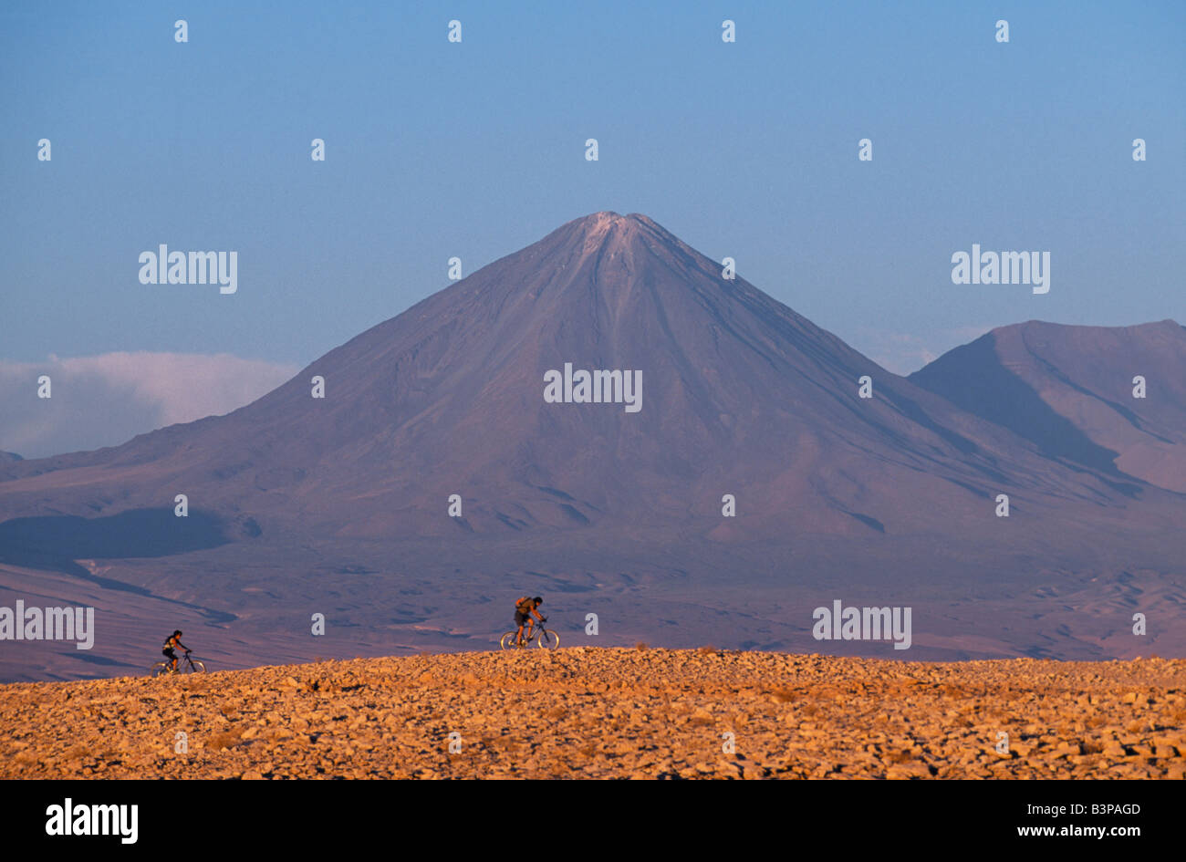 Chile, Atacama Desert. Mountain biking in the Atacama Desert against a backdrop of the perfect cone of Volcan Licancabur 5916 m Stock Photo
