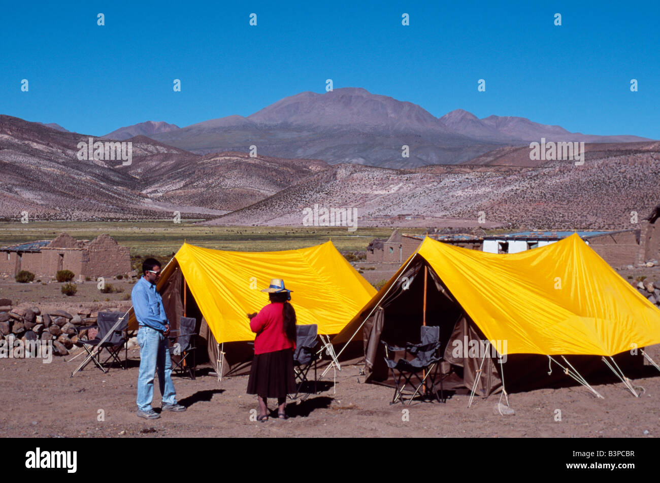 Chile, Region II, Parque Nacional Volcan Isluga. An Aymara woman talks to a tourist at Explora's tented camp in Parque Nacional Stock Photo