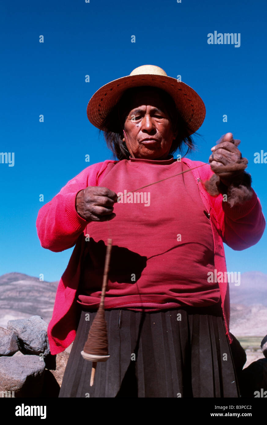 Chile, Region II, Parque Nacional Volcan Isluga. An Aymara woman spins wool by hand Stock Photo
