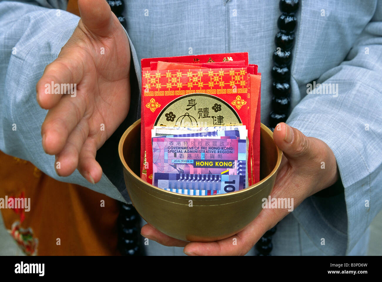China, Hong Kong, New Territories. The hands of a monk extends out for