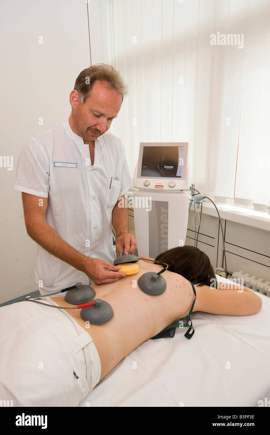 Masseur arranging the essential supplies for an electro-therapeutical treatment on a female patient Stock Photo