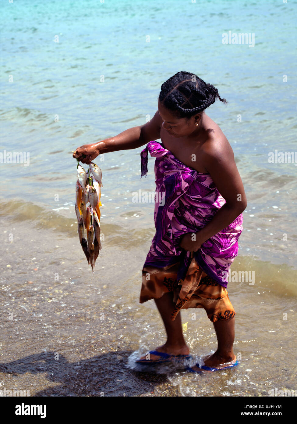 Northern Madagascar, Washing the day's catch! A Malagasy woman with fish she has bought from fishermen in a fishing village just outside Antsiranana, more commonly known as Diego after the Portuguese captain, Diego Suarez, who sailed there in 1543. Antsiranana means 'port' in the Malagasy language.Diego's deep-water harbour encircled by hills is of strategic importance to Madagascar. Stock Photo