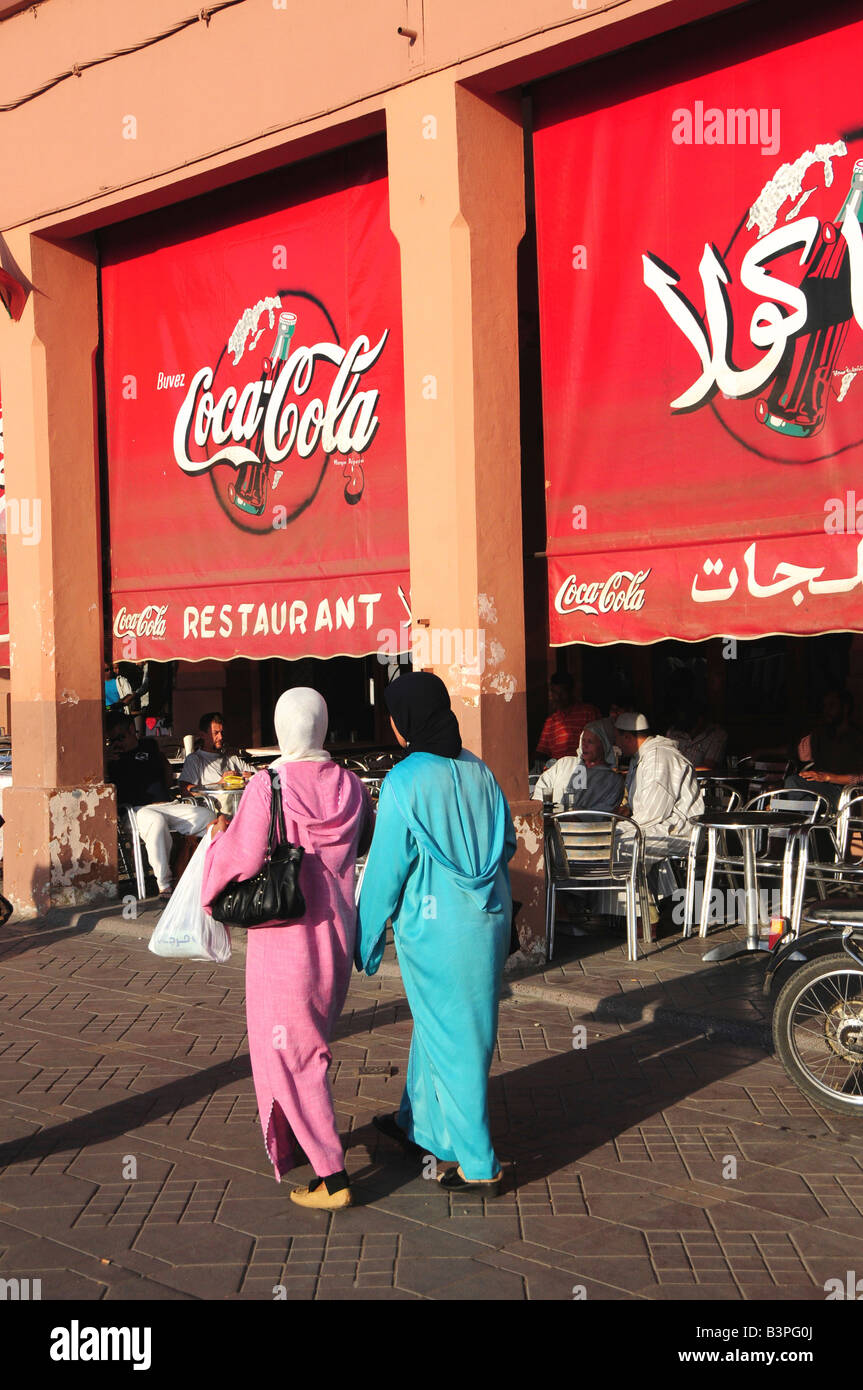 Two veiled women in front of arabic coca-cola advertisement in Djemma el-Fna Square, 'Imposter Square' or 'Square of the Hanged' Stock Photo