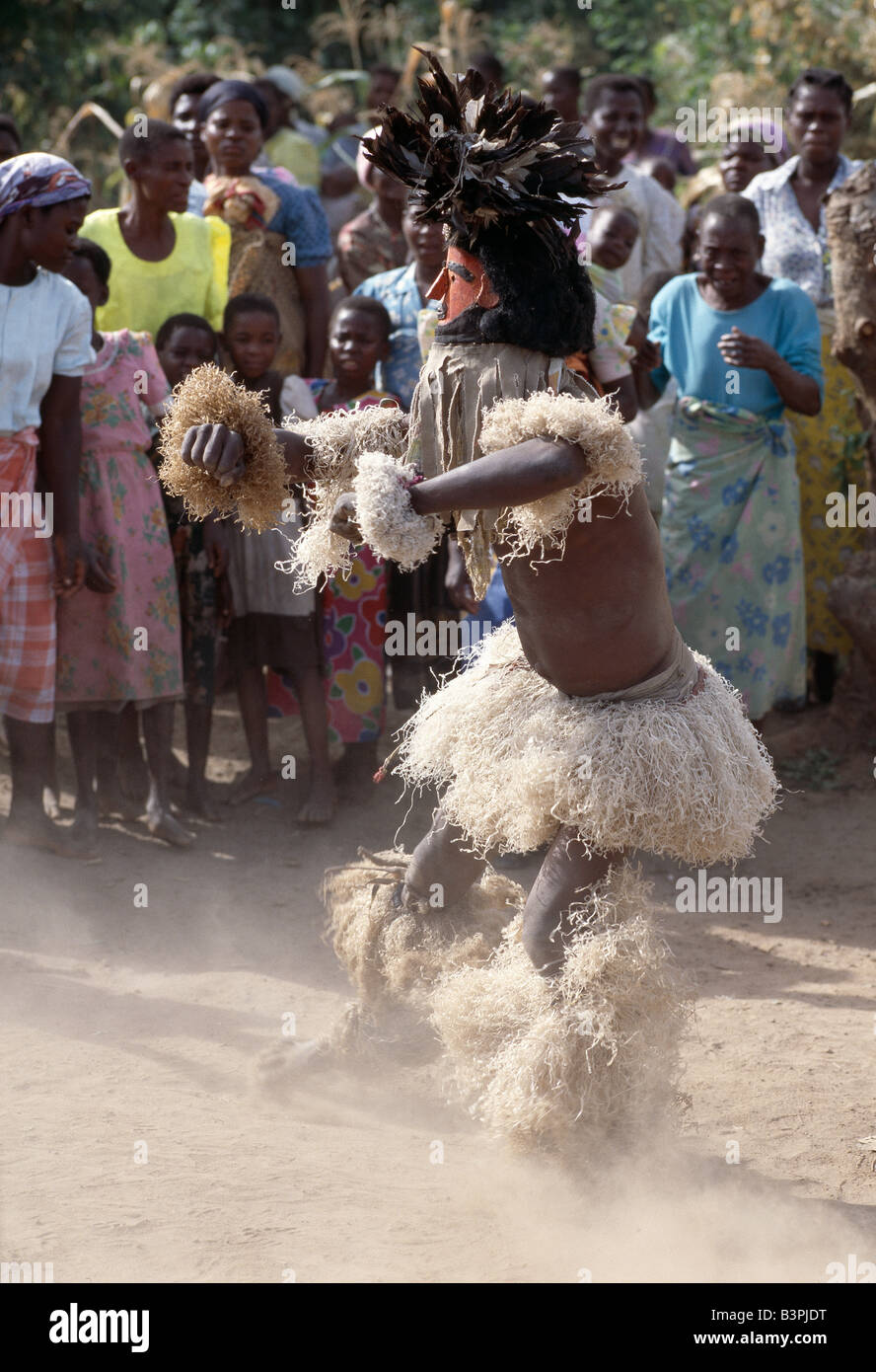 Malawi, Mua, Central Malawi. The Chewa people, Malawi's largest ethnic group, live on the west side of Lake Malawi. Despite years of missionary influence, they still cling to old beliefs and rituals. For them, death simply means a journey of rebirth into the spirit world. The terrestrial representatives of this other world are grotesquely masked dancers known as Gule Wamkulu. When a person dies, masked dancers appear at the funeral to welcome the deceased to the spirit world. Stock Photo