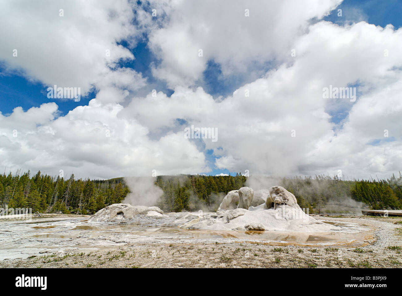 Twin geysers steaming under a cloudy blue sky in Yellowstone National Park Stock Photo