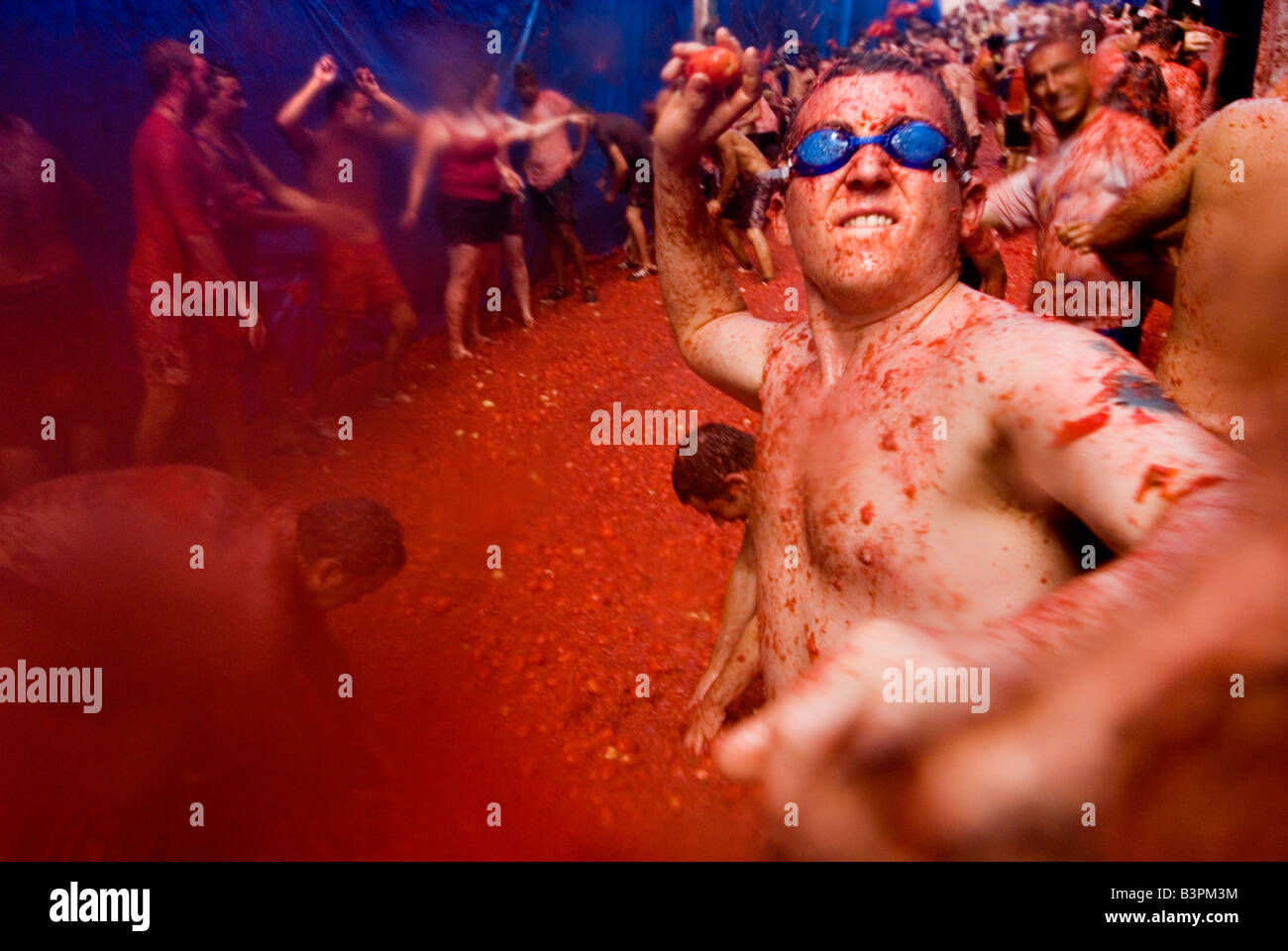 Man wearing swimming goggles throwing a tomato at La tomatina food fighting festival. Bunol. Valencia Spain Stock Photo