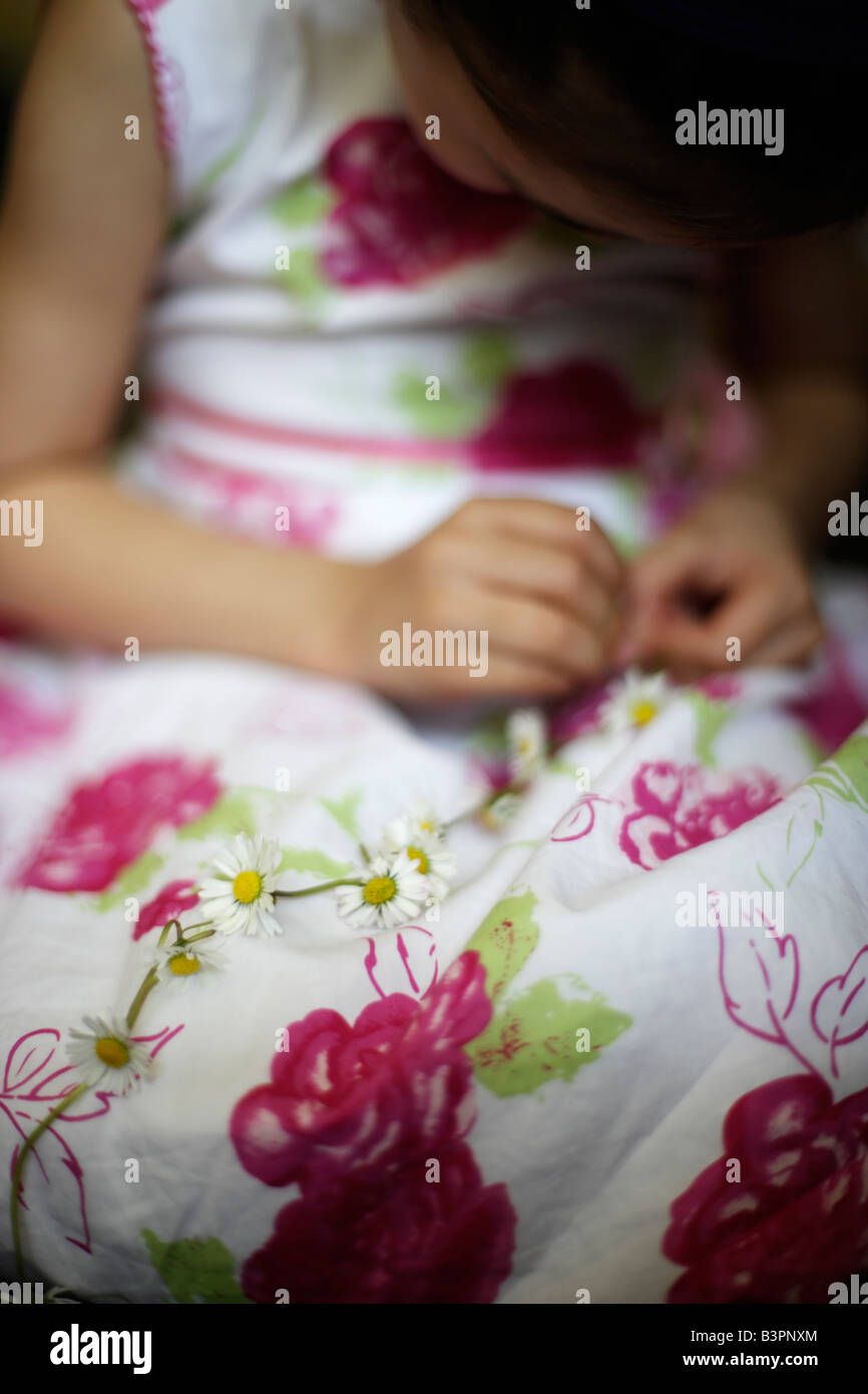 Five year old girl makes daisy chain Stock Photo