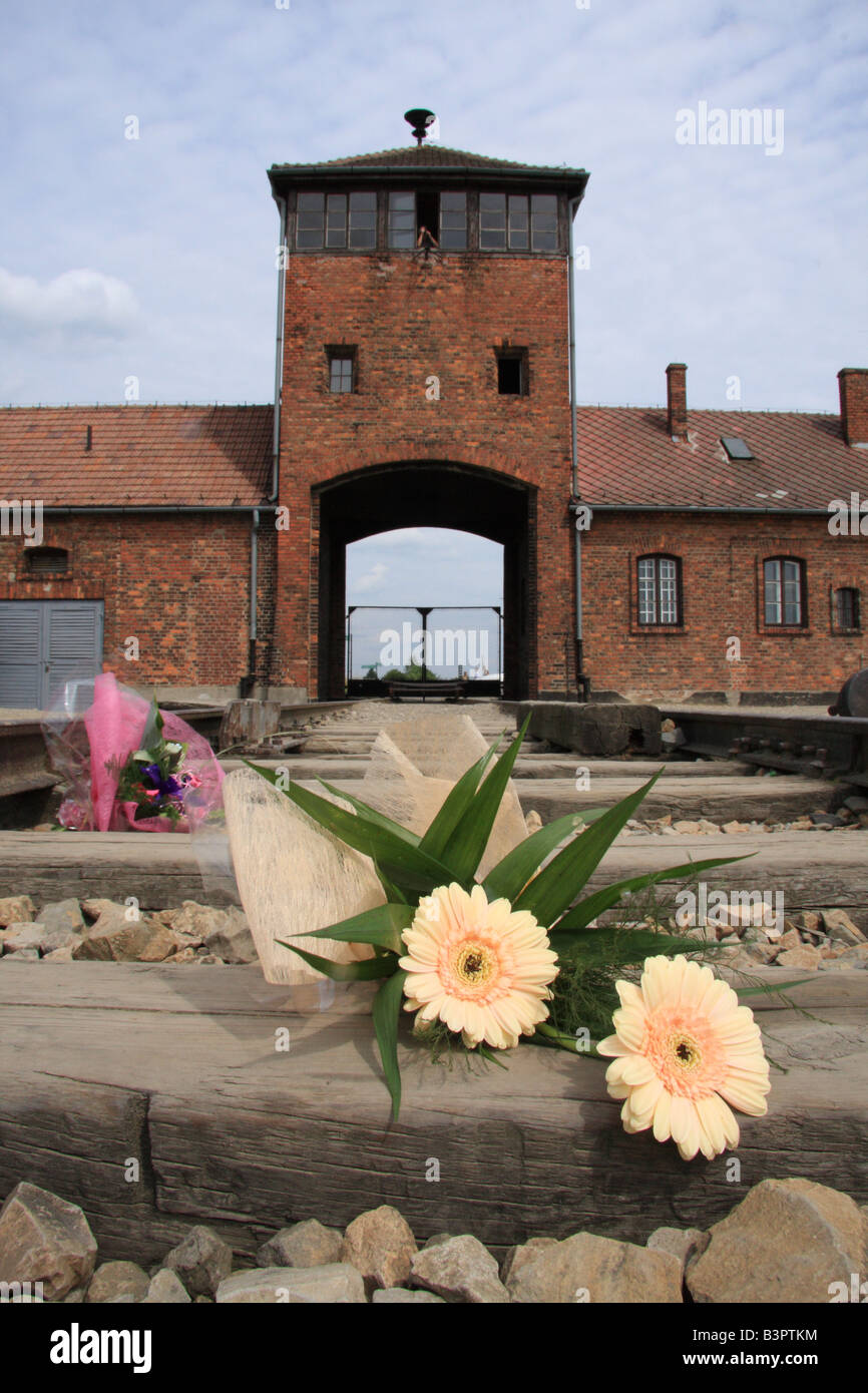 Floral tribute on the rail line by Hell's Gate; the main entrance to Auschwitz-Birkenau concentration camp, near Krakow Poland Stock Photo