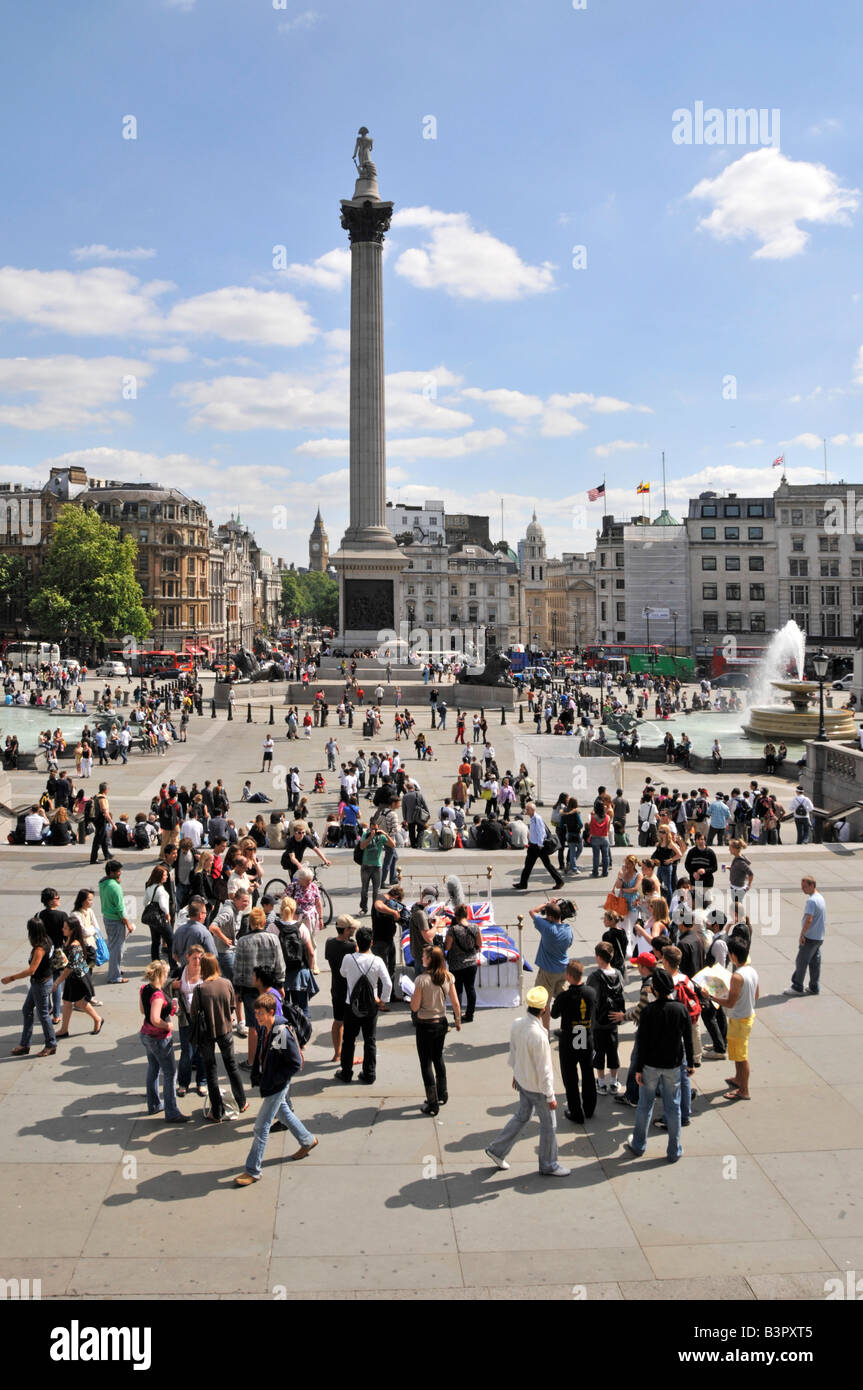 Blue sky sunny summer day for sightseeing tourism visitors to iconic busy Trafalgar Square & historical Nelsons column and fountains London England UK Stock Photo