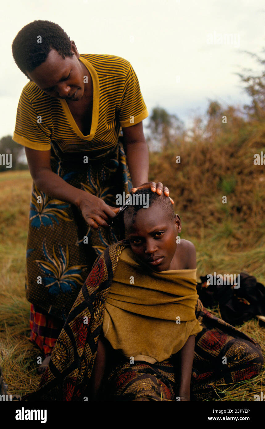 Young woman getting a haircut in a camp for displaced Tutsis living in camp under army protection near Mwaro, Mugamba Province Stock Photo