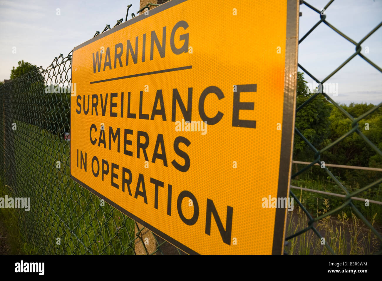 warning sign for surveillance cameras on mesh fence protecting private property Stock Photo