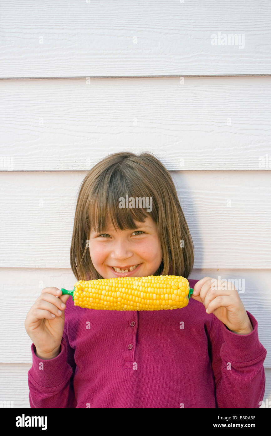 Young girl with teeth missing eating corn on the cob Stock Photo