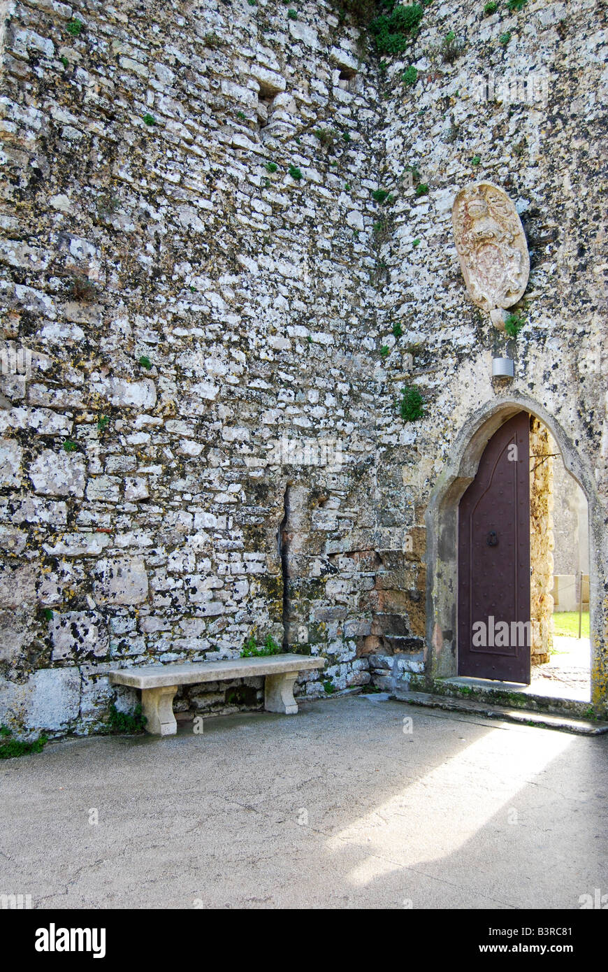 An empty bench next to a half open door in a castle wall Stock Photo