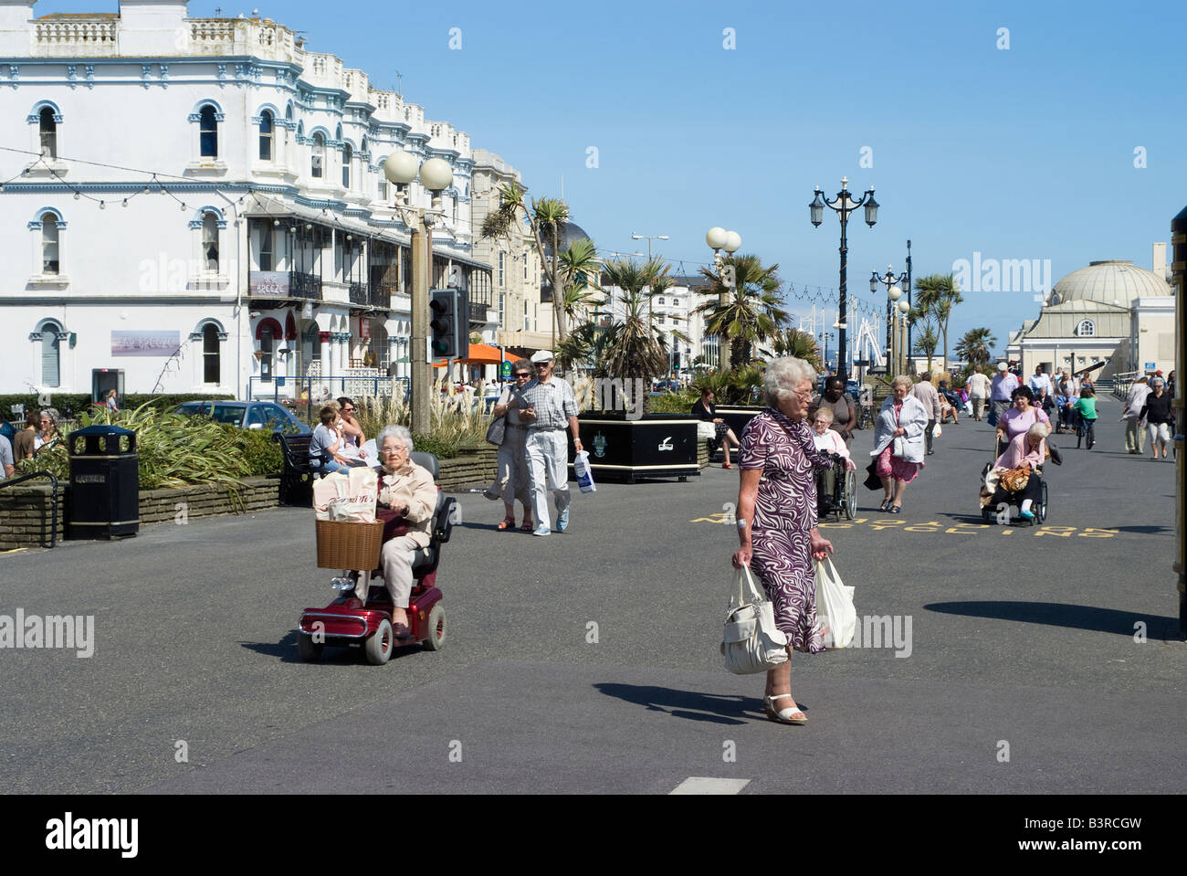 Seaside resort elderly people walking along the promenade Worthing West Sussex England Stock Photo