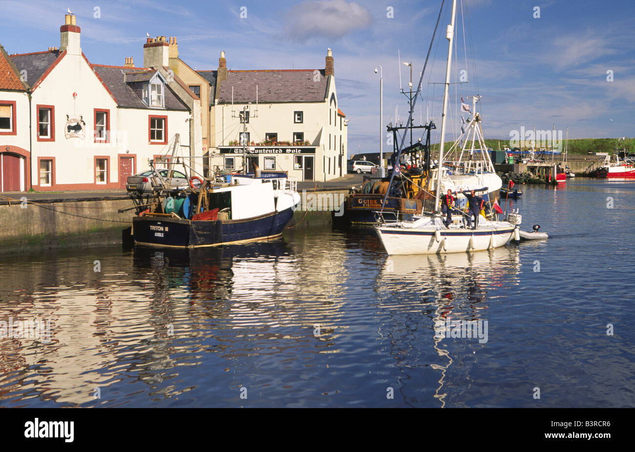 Yacht coming into port berth on a quiet still morning in scenic ...