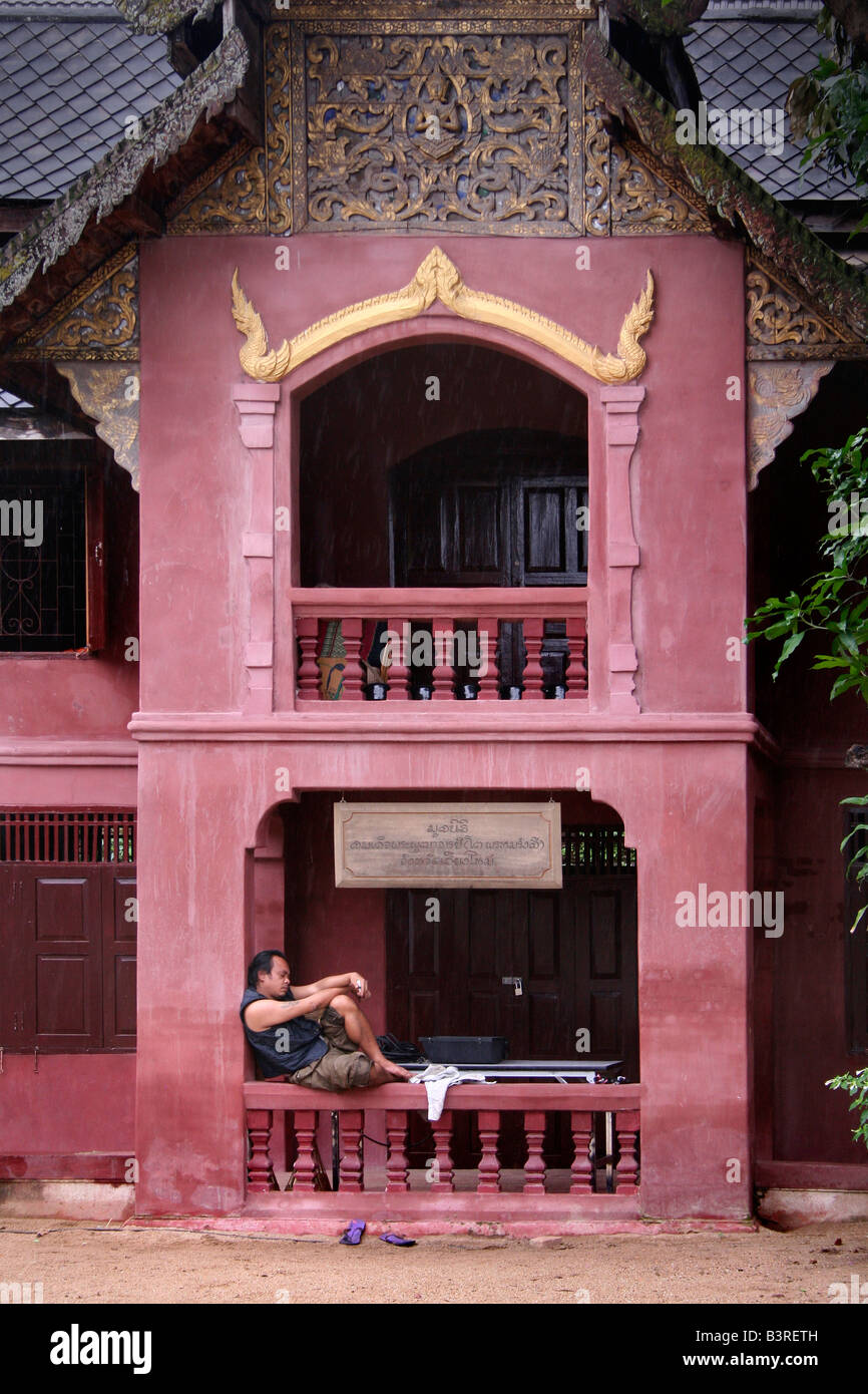 A Thai man relaxes on the terrace of a traditional house Stock Photo