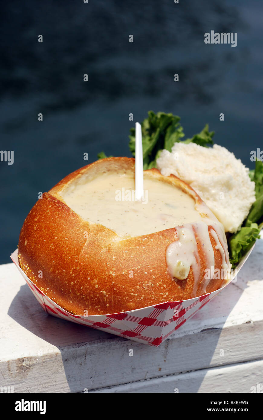 Clam chowder in a sourdough bread bowl on a wooden fishing dock Stock
