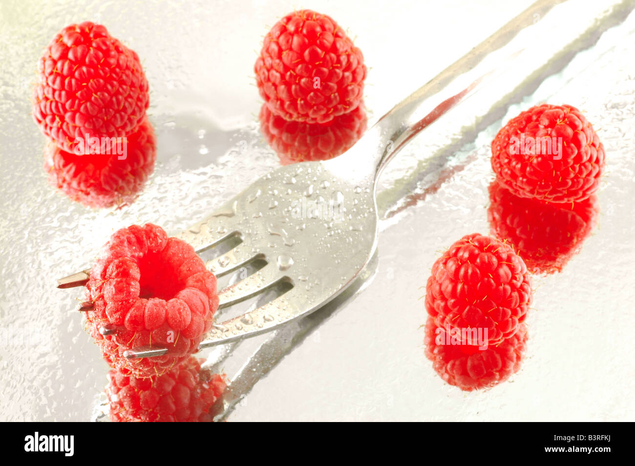 Fresh chilled raspberries on a reflective background with a shallow depth of field Stock Photo