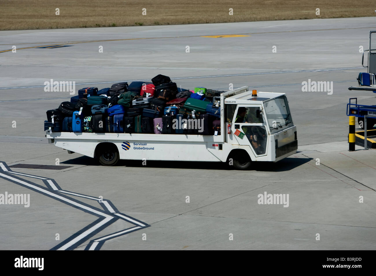 Baggage handler moving luggage at airport air side British Airport Jersey Channel Islands Stock Photo