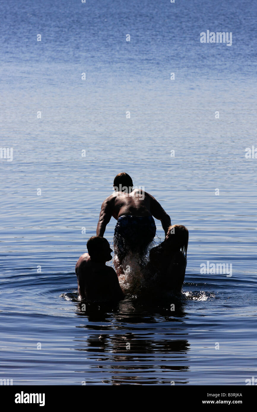 Deer Lake in Michigan USA Three boys brothers men Caucasian having fun playing in water jumping to water jump vertical hi-res Stock Photo