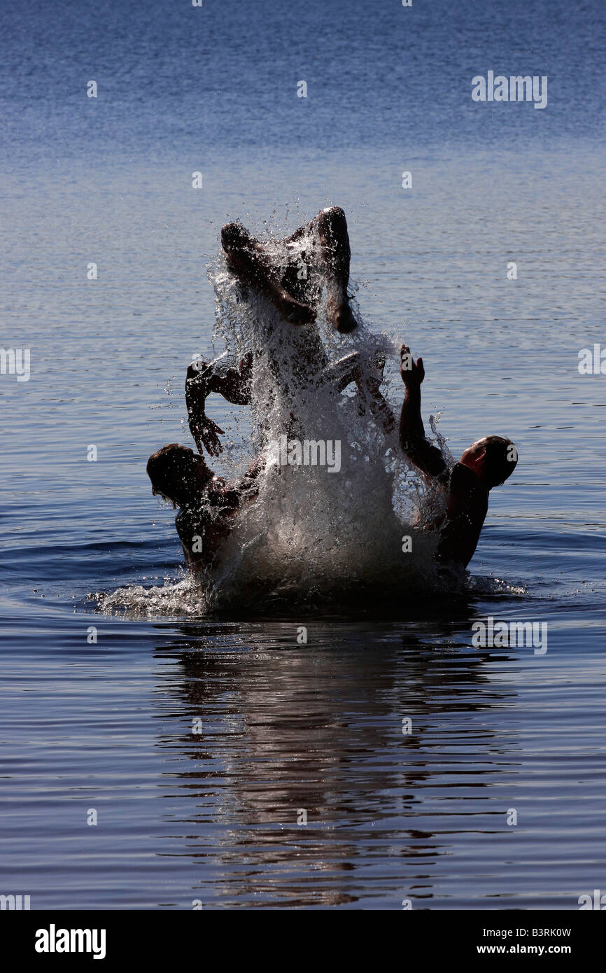 Deer Lake in Michigan USA Three boys brothers men Caucasian having fun playing in water jumping to water jump vertical hi-res Stock Photo