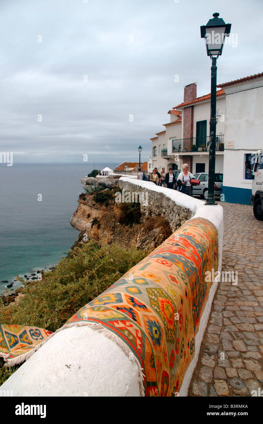 A clifftop street of the coastal resort town of Nazaré, Portugal. A patterned carpet  is draped over the wall to air. Stock Photo