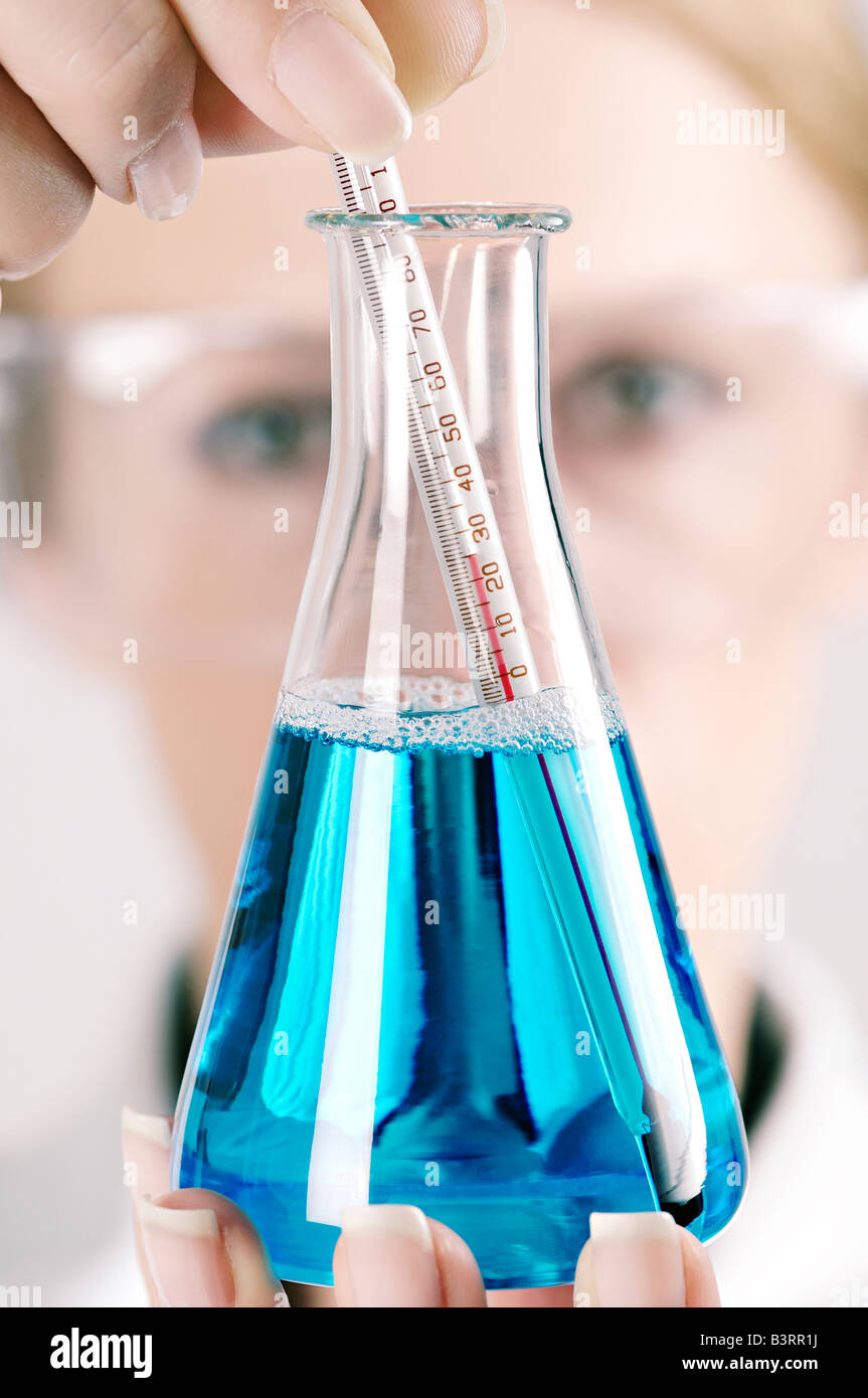 Scientist with a Conical Flask and Thermometer in a Laboratory Close Up Stock Photo