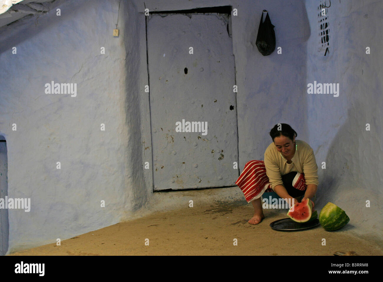 A young woman cuts up a refreshing cool water melon in the summer heat. Stock Photo