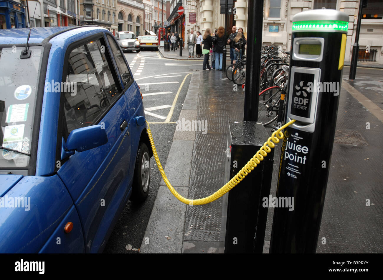 An electric car  (a Reva G Wiz carbon neutral electric car) charges up using a street juice point in central London Stock Photo