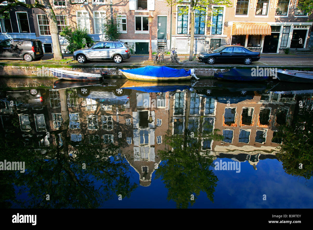 Typical Amsterdam street along canal with Dutch bikes, boats, cars and