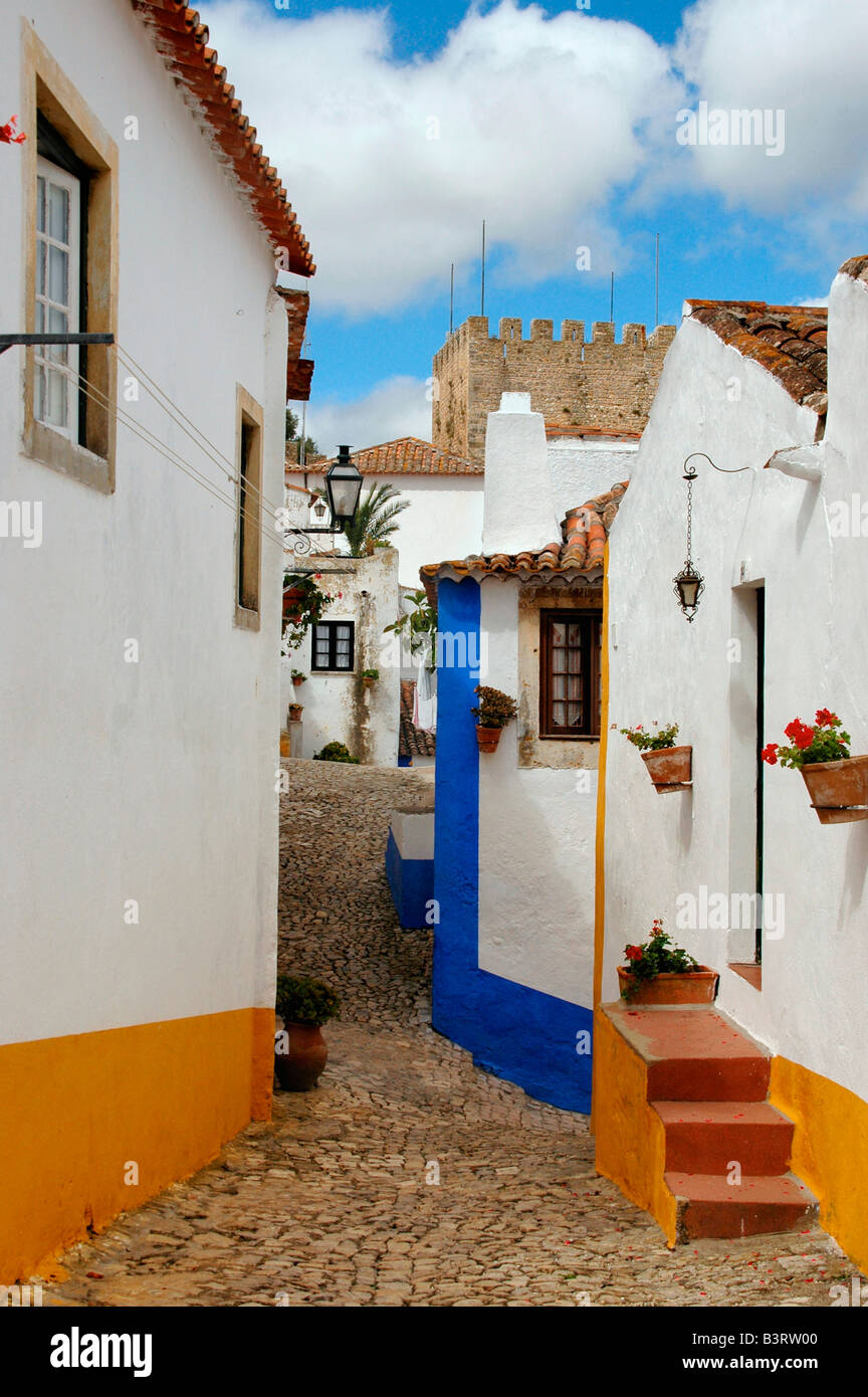 A street scene within the preserved medieval town of Obidos, Portugal. Part of the castle is visible in the background. Stock Photo