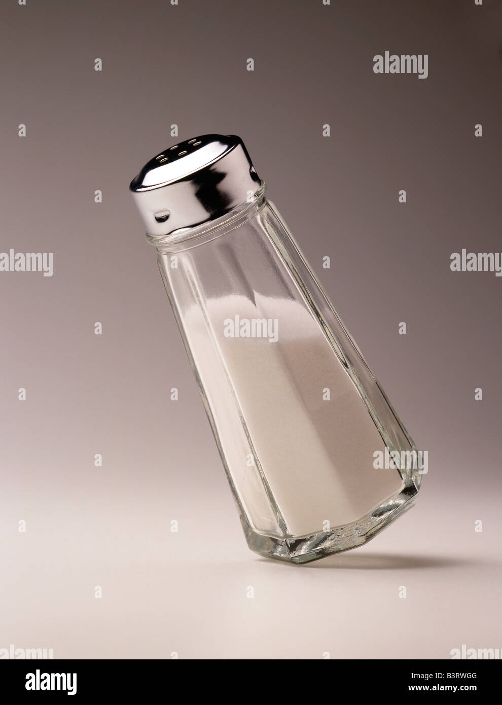 STILL LIFE IMAGE OF A SALT SHAKER BALANCED CAREFULLY ON A FEW GRAINS OF