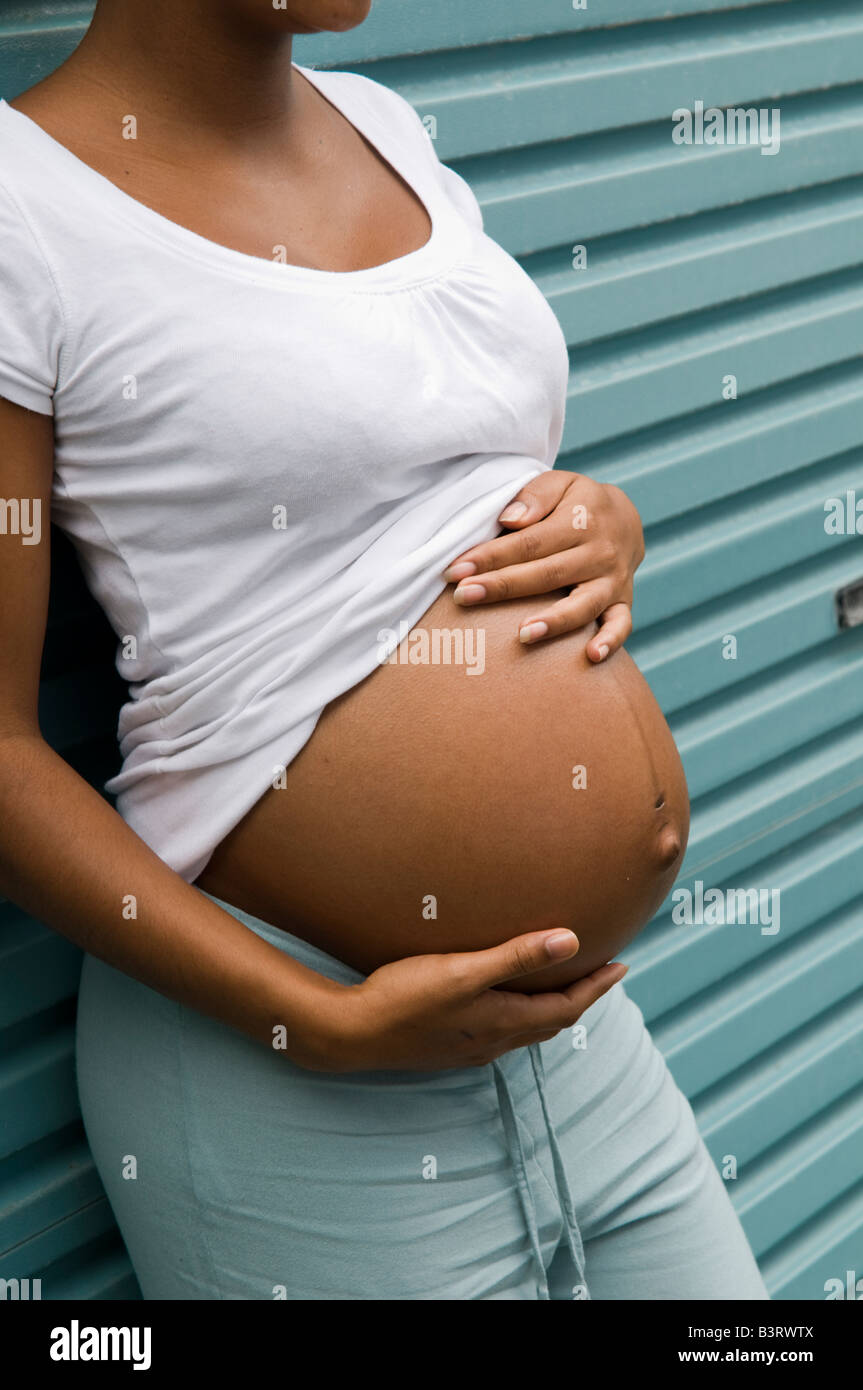 Pregnant Black Unmarried Teenage Single Mother Girl Alone Holding Her Big Belly Leaning Against