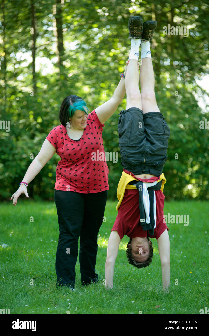 teenage boy doing a handstand helped by teenage girl Stock Photo