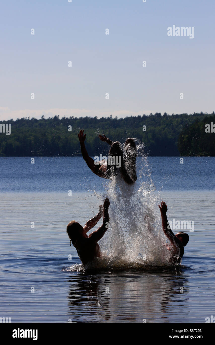 Deer Lake in Michigan USA Three boys brothers men Caucasian having fun playing in water jumping to water jump vertical hi-res Stock Photo
