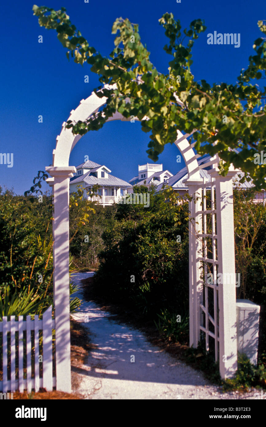 Seaside Florida walkway with white wooden arch and green plants pastel buildings in the background Stock Photo