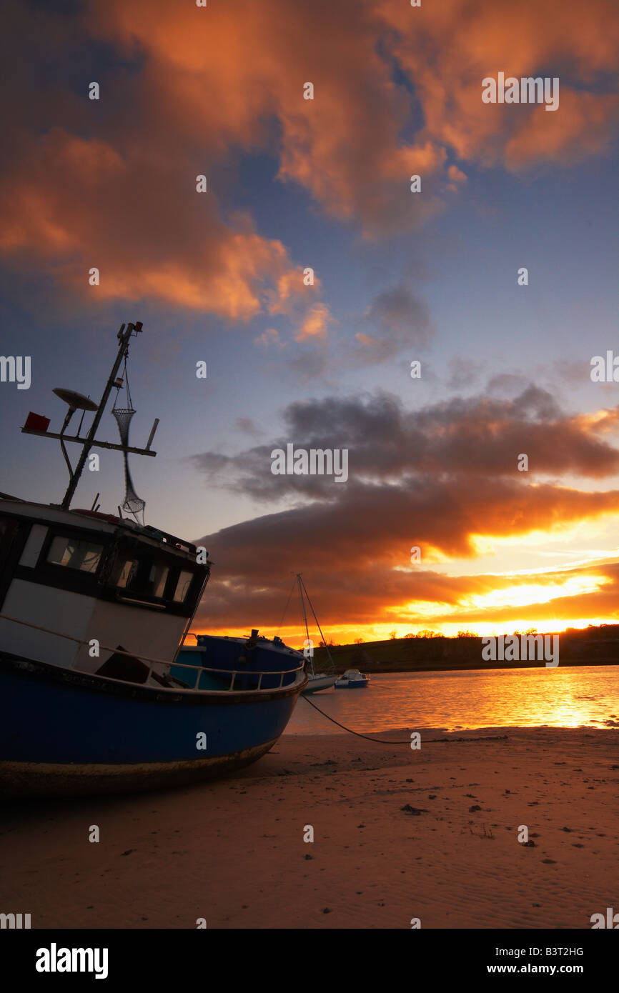 Old fishing boat moored in Alnmouth estruary at low tide and backed by ...