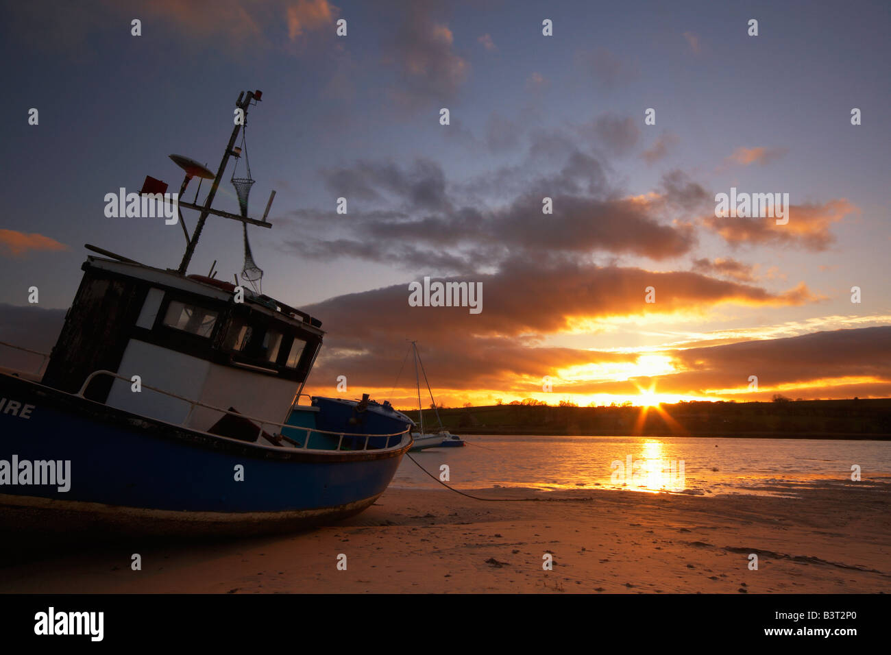 Old fishing boat moored in Alnmouth estruary at low tide and backed by ...