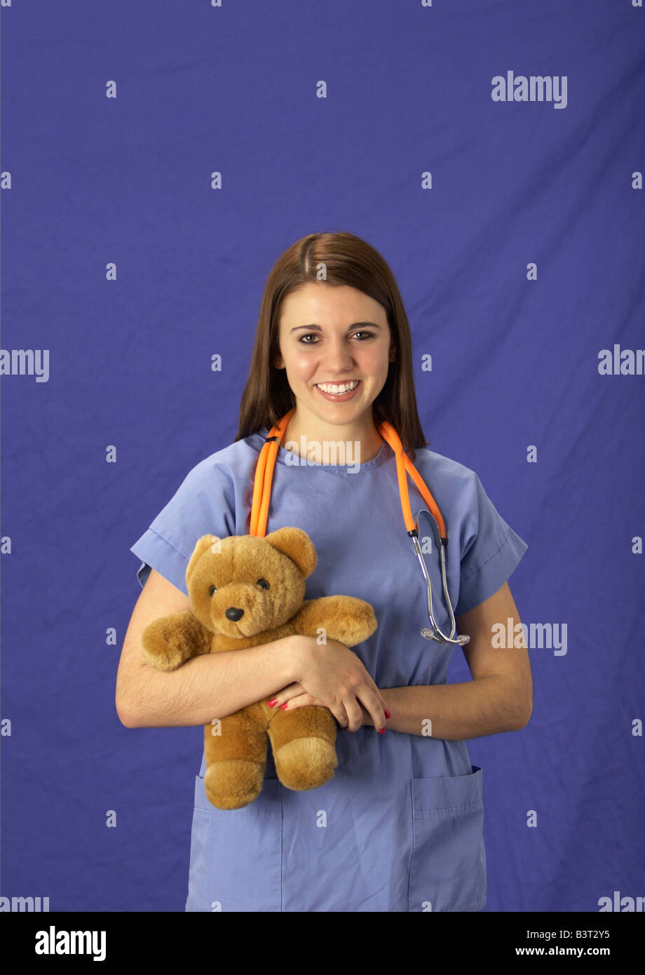 Young woman in pediatric nurse scrubs with a teddy bear and stethoscope