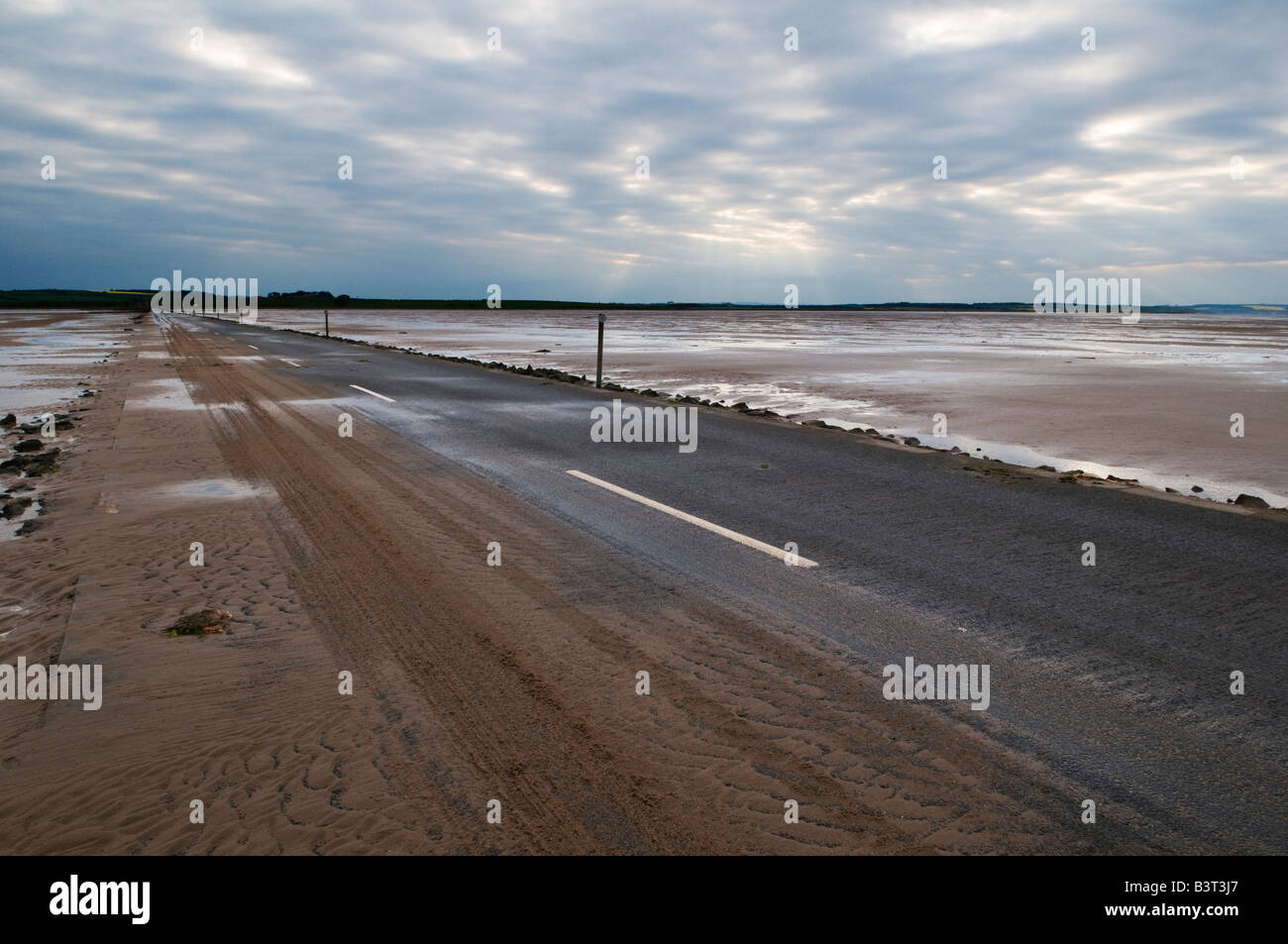 looking towards mainland from sand covered road from Lindisfarne - Holy island at low tide, Lindisfarne, England Stock Photo
