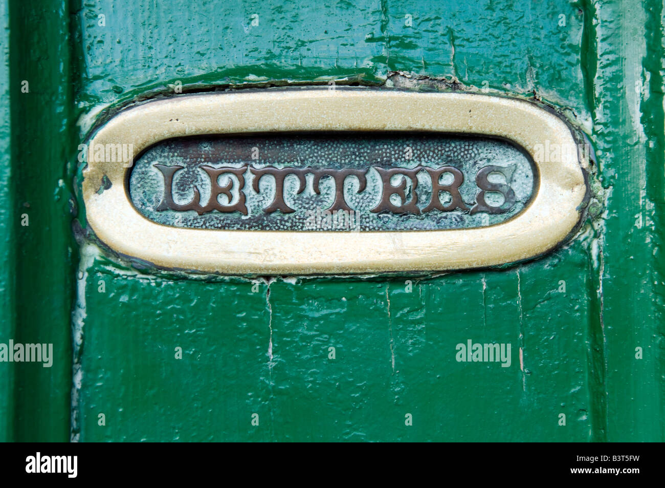 Old Gold plated letter box in a green door Stock Photo