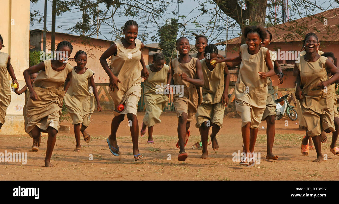 Group of girls in their beige school uniforms running at the break in the courtyard (MR) Stock Photo