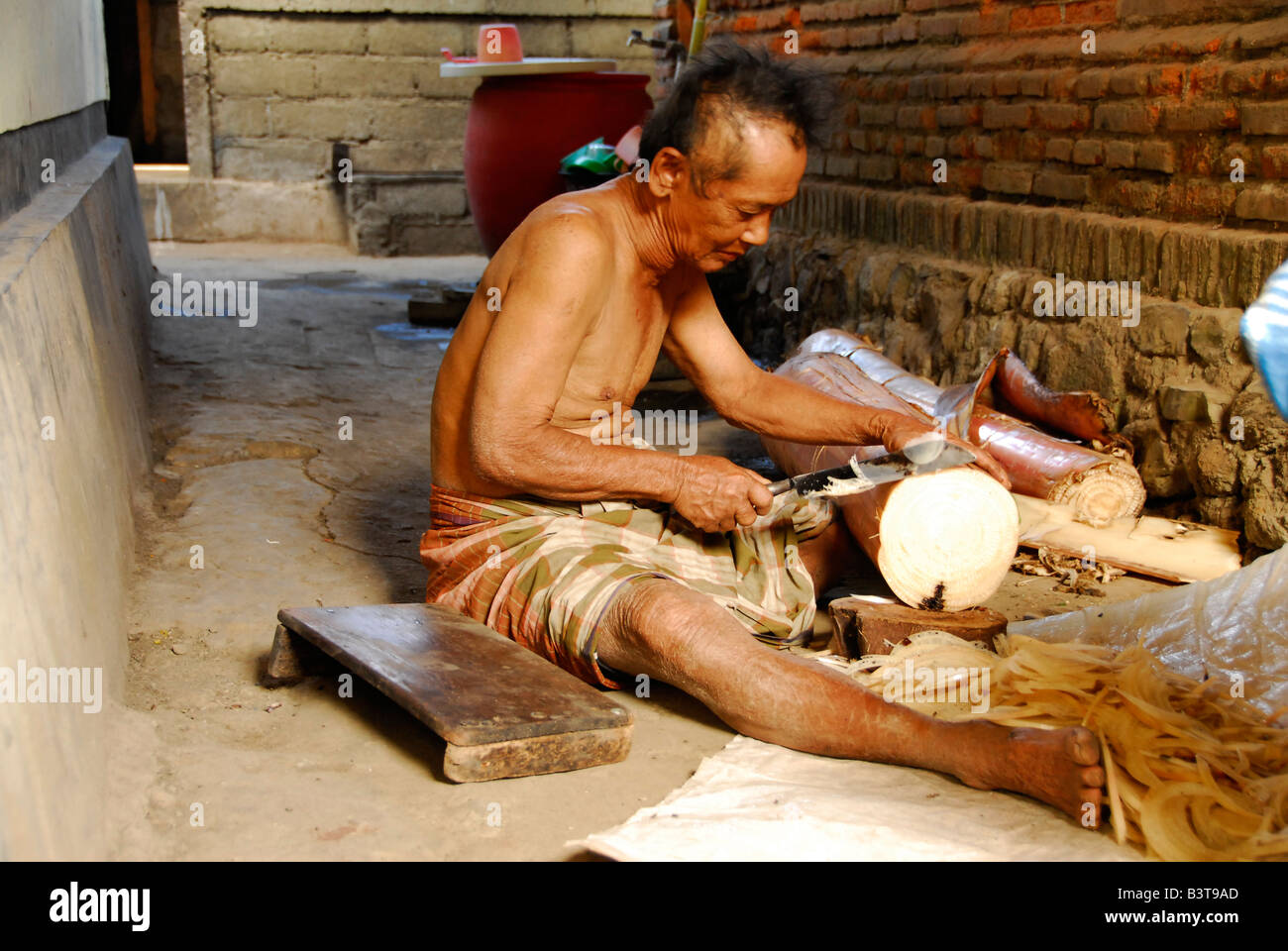 man cutting banana tree for firewood,julah, bali aga village , north bali , indonesia Stock Photo