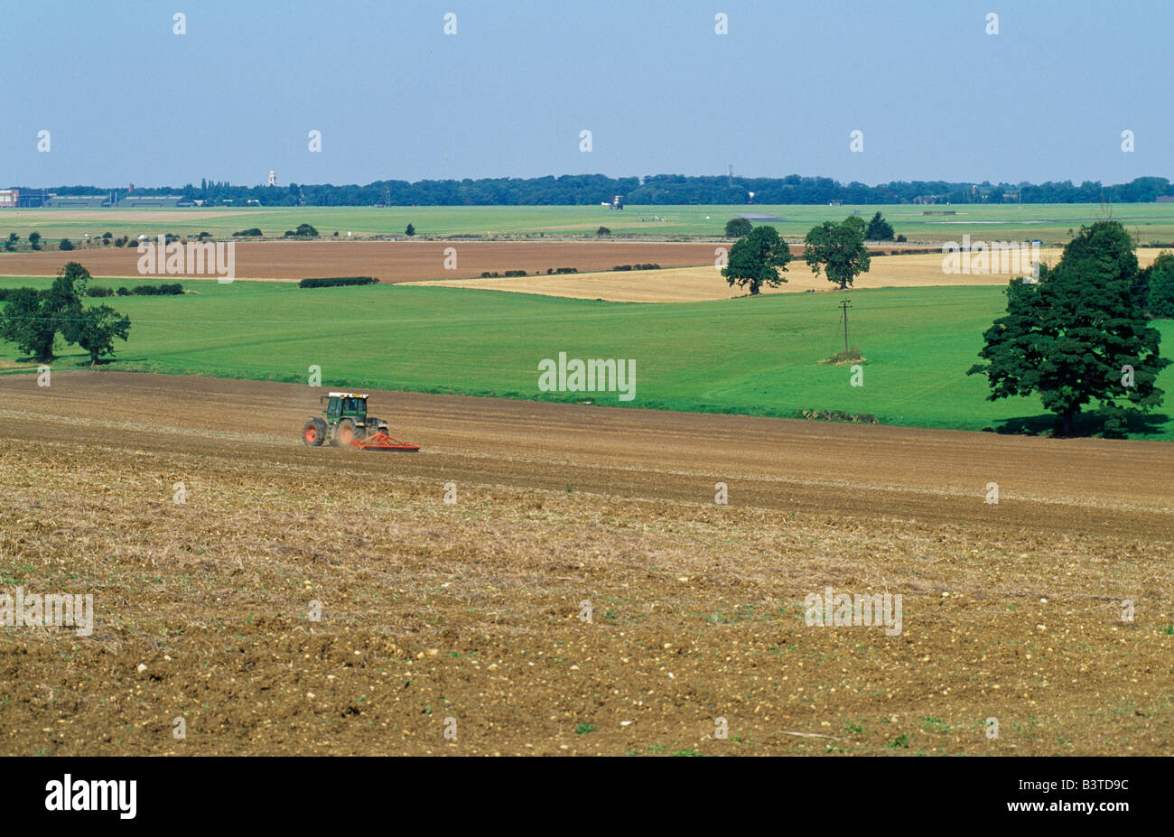 England, Lincolnshire, Cranwell. Tractor rolling a ploughed field with view over RAF Cranwell. North Kesteven. Stock Photo